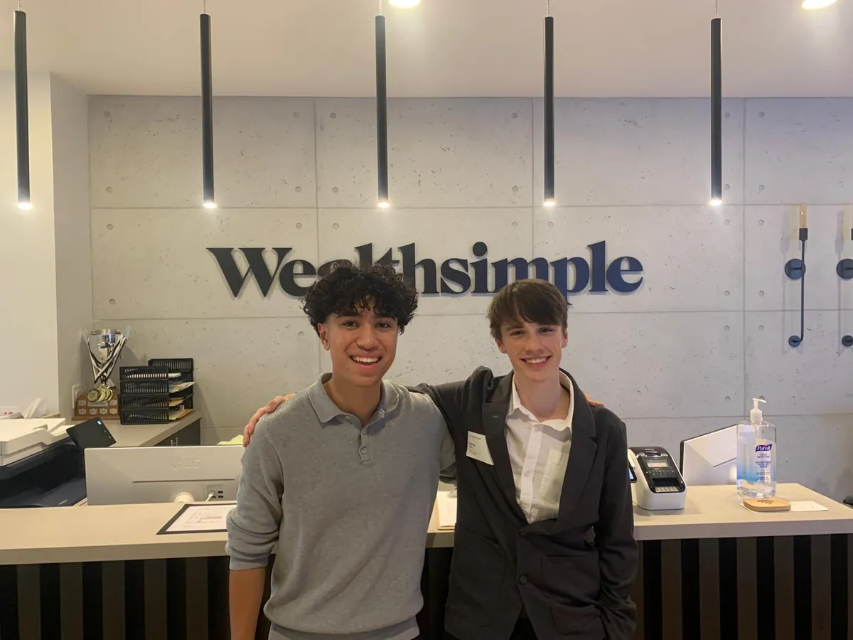 Gabriel and Noah Barbaros stand together beneath the Wealthsimple sign during a visit to its Toronto headquarters.