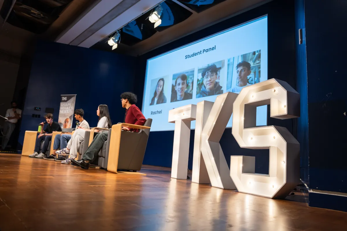 Four students sit on stage beneath a āStudent Panelā slide at the TKS Vancouver Showcase.