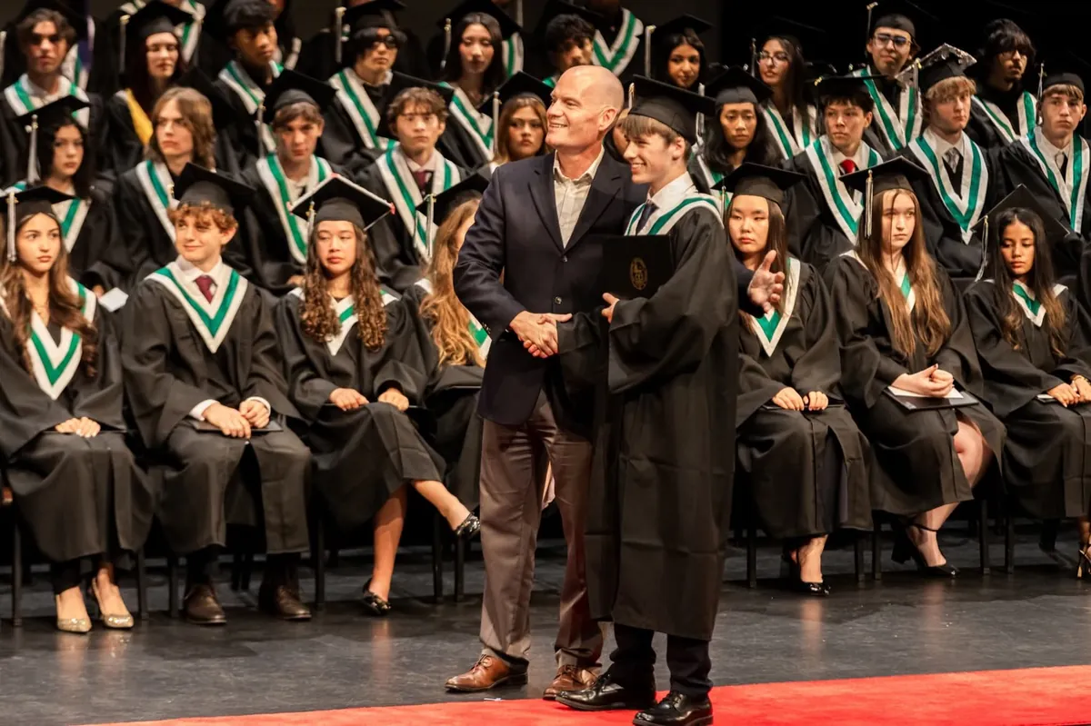 Gabriel receives his diploma from principal Tyler Evans on stage with the Class of 2026.
