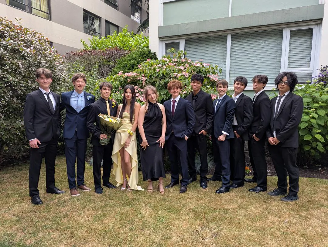 Gabriel and his friends pose in formal clothes on a lawn before prom.