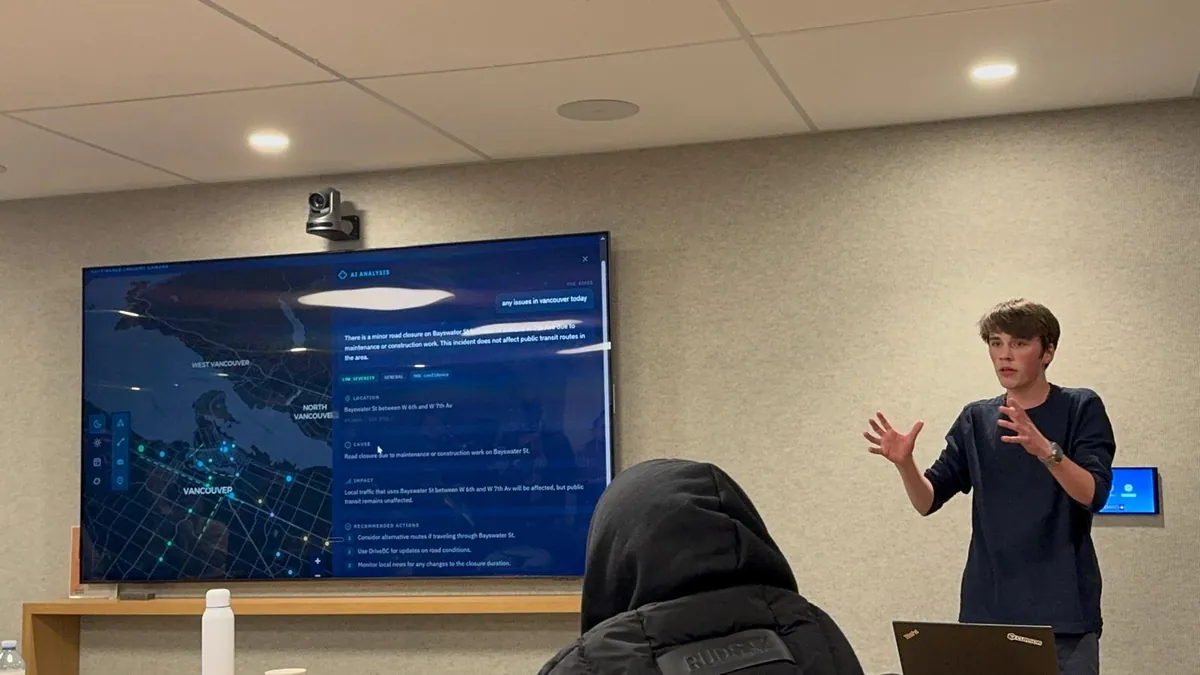 Gabriel presents Situate Vancouver at the Cursor Hackathon beside a screen showing its map and local alerts.