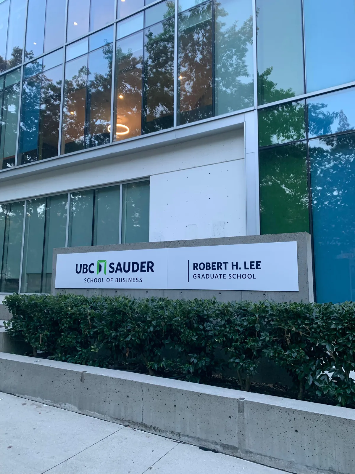 UBC Sauder School of Business and Robert H. Lee Graduate School signs outside the glass-fronted building.
