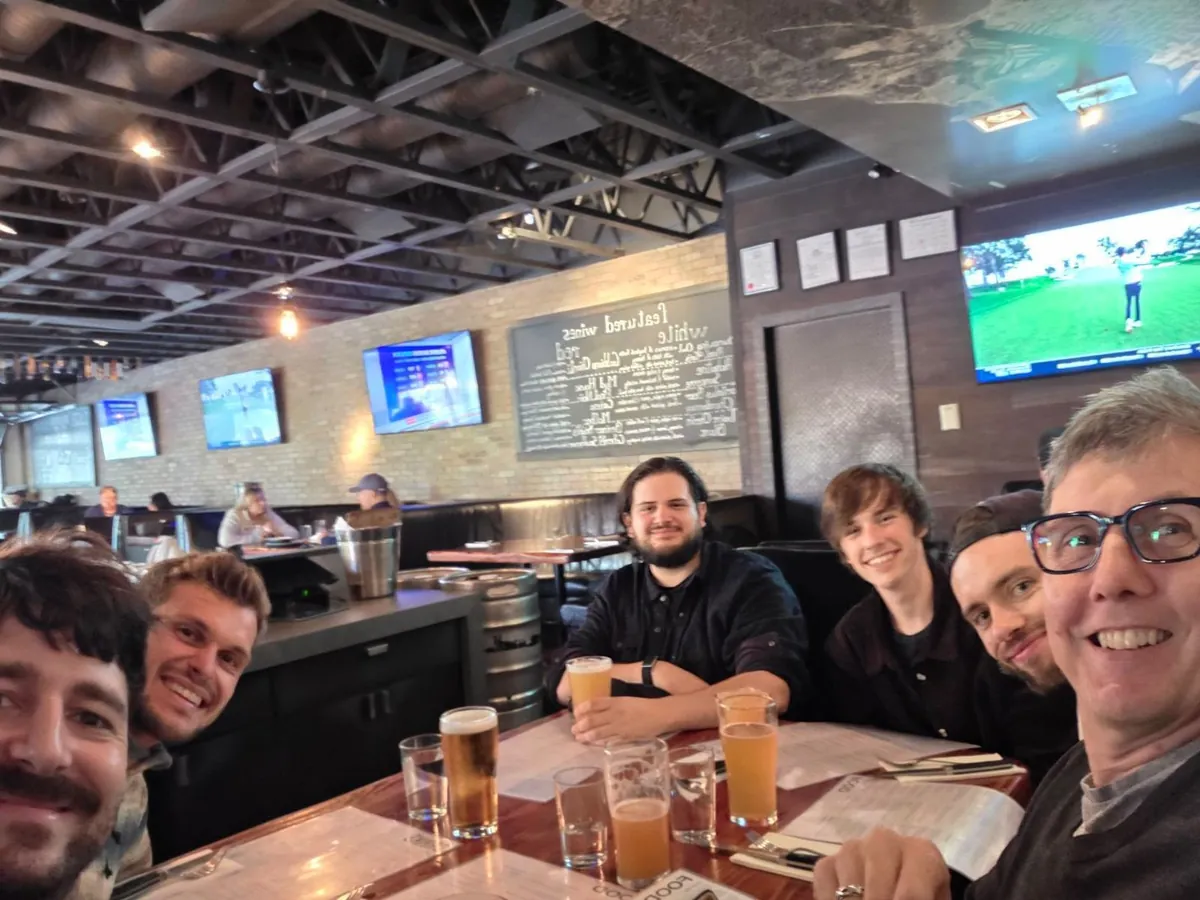 Gabriel and Plastic Bank colleagues gather around a table for farewell drinks.