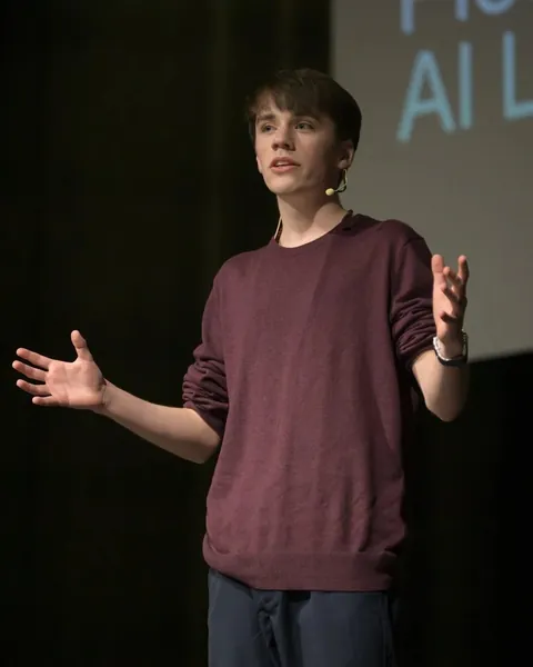 Gabriel Dalton on stage giving his TEDx talk, wearing a headset microphone